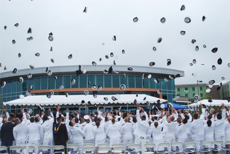 West Point cadets at high school graduation throwing caps in the air