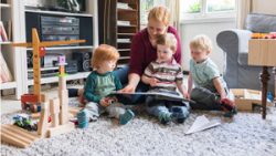 Mother and three sons looking at picture book together